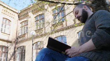 一个快乐的留胡子的人<strong>正在</strong>城市公园里休息，他<strong>正在看书</strong>